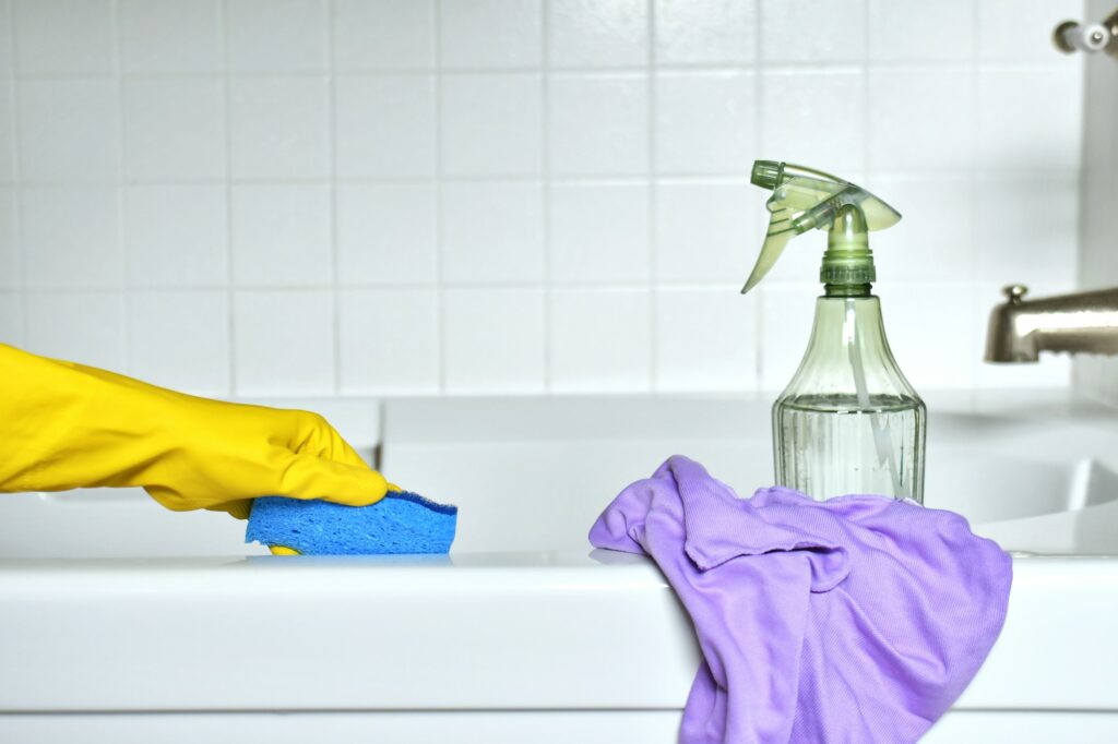 Cleaning a bathroom bathtub and shower combination. Scrubbing a tub with a sponge scrubber.