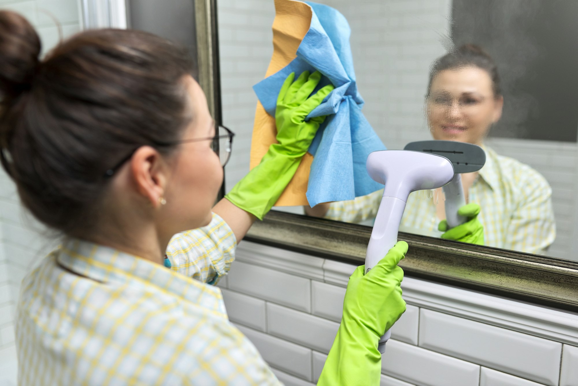 Close-up of gloved hands with steam in mirror, eco-friendly cleaning