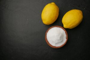 Coarse salt in a bowl and lemon on black background