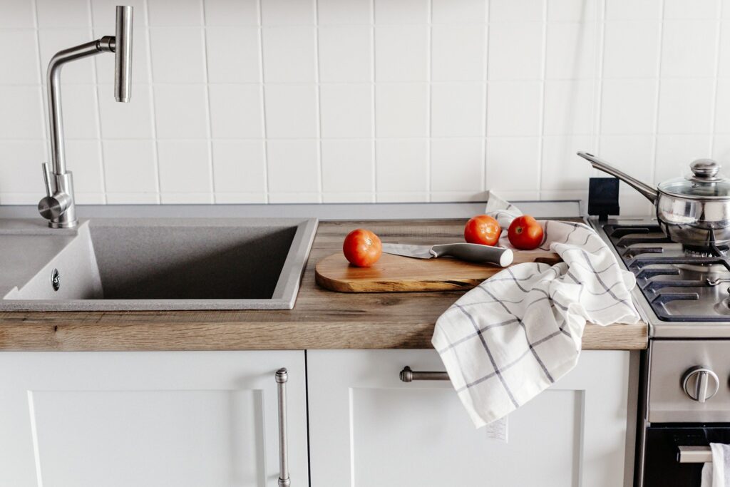 Cooking food on modern kitchen with steel oven, pots, knife on wooden cutting board