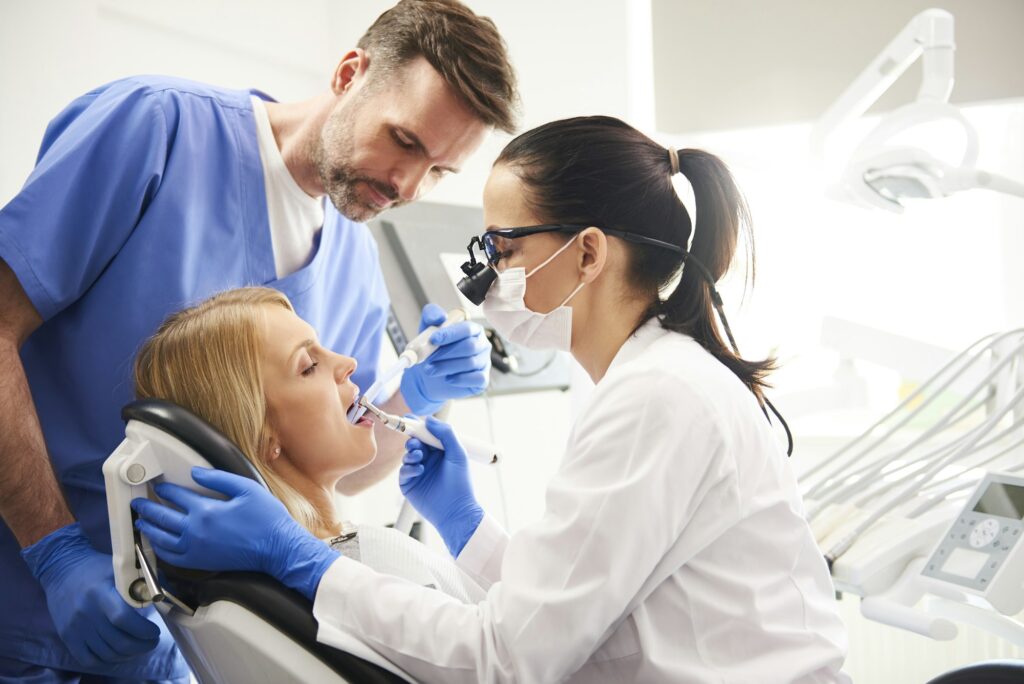 Dentist and her assistant doing their work in dentist's clinic