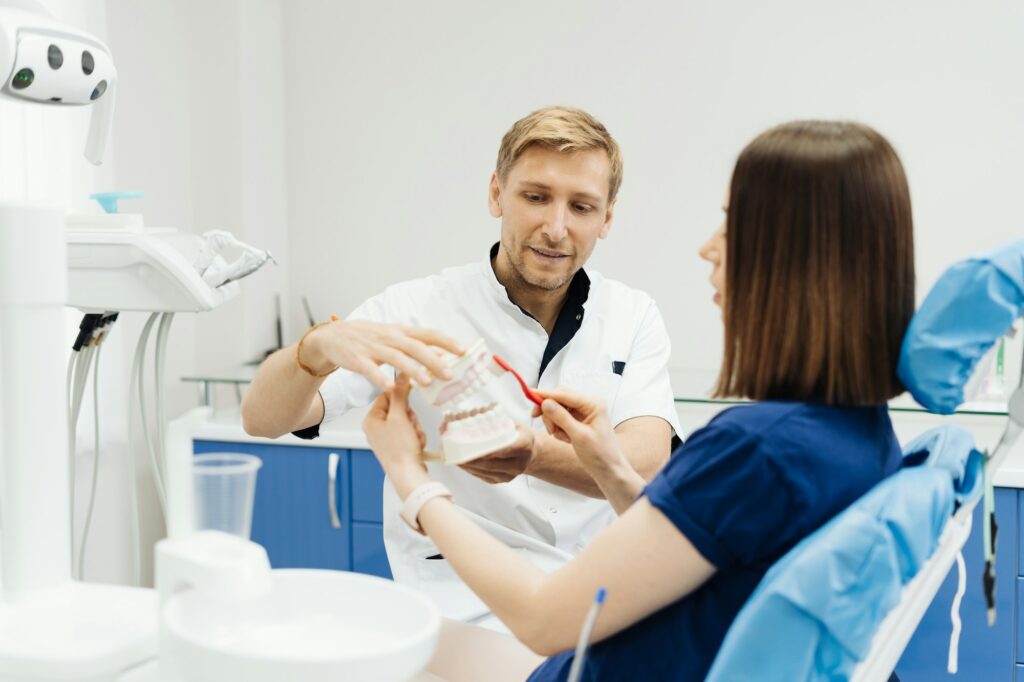 Dentist showing the correct dental hygiene on white background