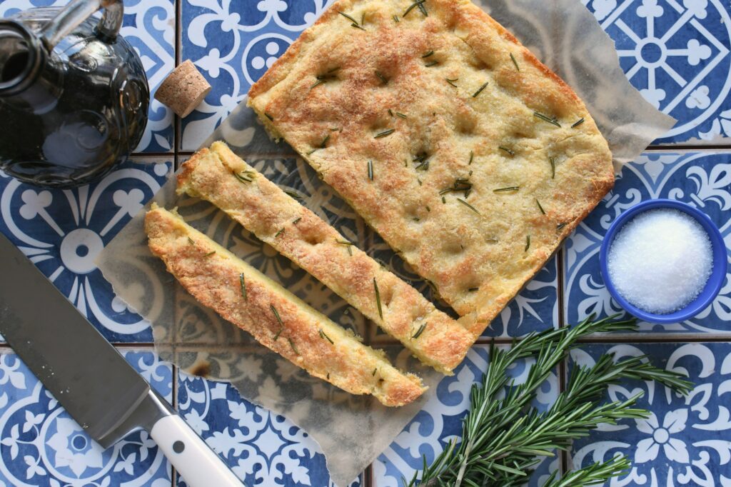 Focaccia Bread with fresh rosemary herbs aka pizza bianca on tiles overhead high angle food flat lay