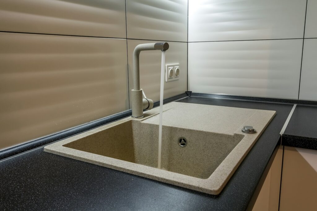 Granite sink and water faucet in new modern kitchen interior