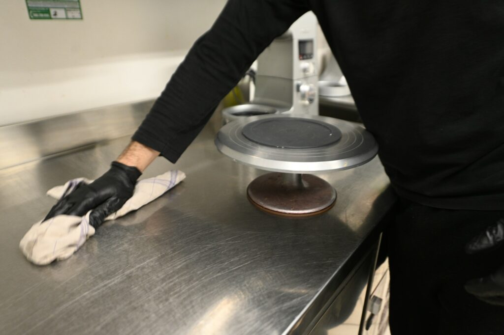 kitchen staff clean steel counter top in restaurant wearing gloves, hygiene concept