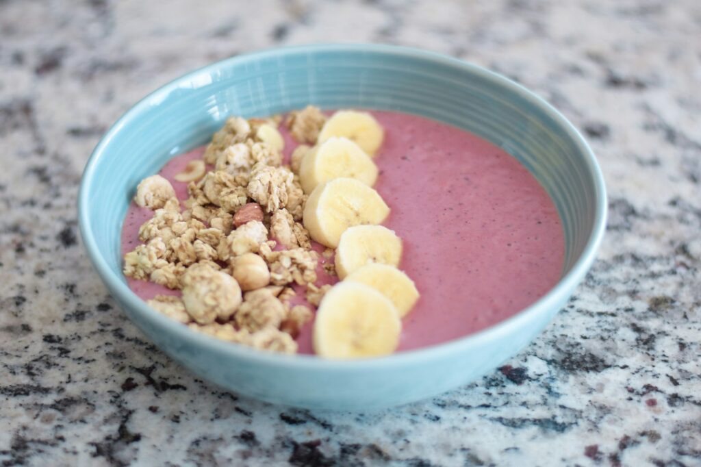 Smoothie bowl with granola cereal and bananas on a granite countertop