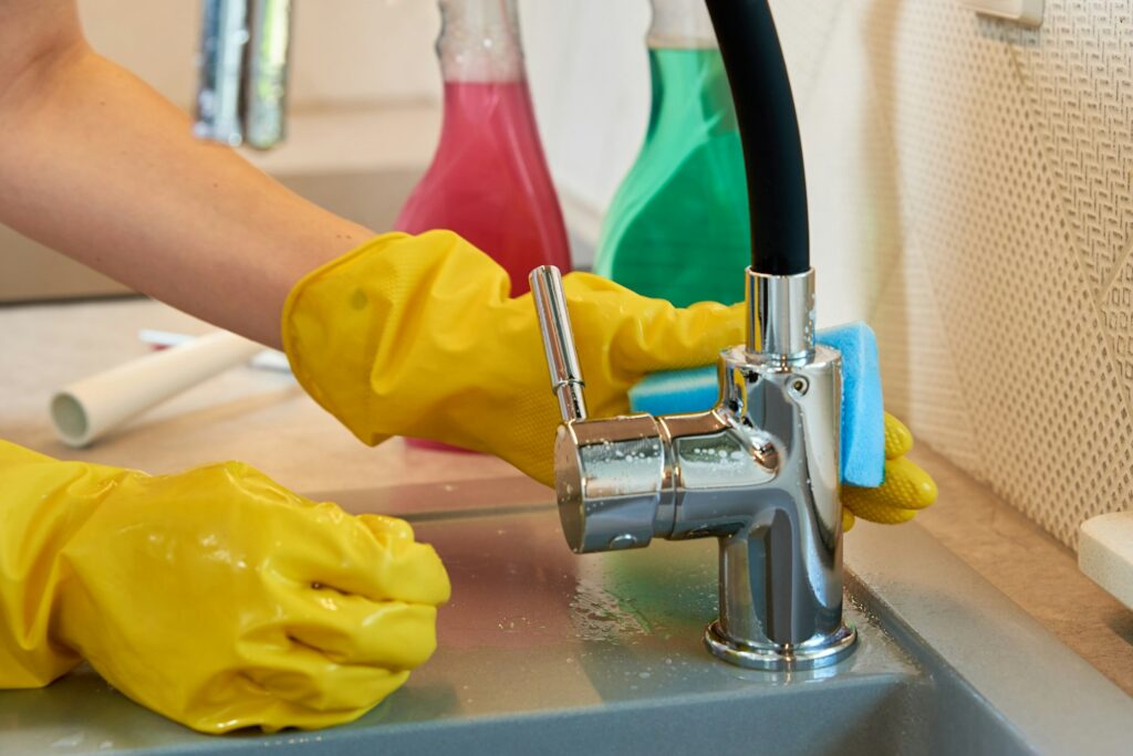 Woman cleaning kitchen sink with water tap