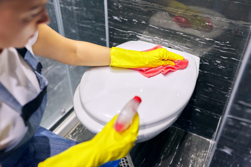 Woman in gloves with detergent washing the toilet close-up