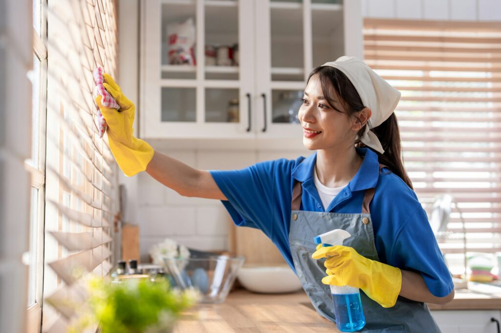 Asian young beautiful female cleaner worker cleaning kitchen at home.