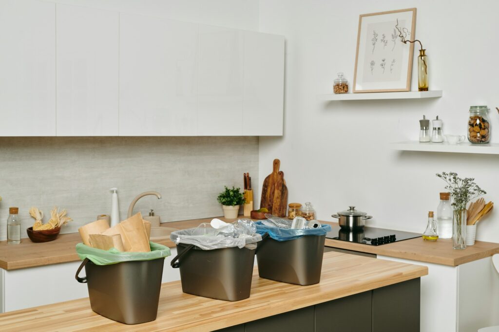 A kitchen with kitchenware and group of plastic trash bins