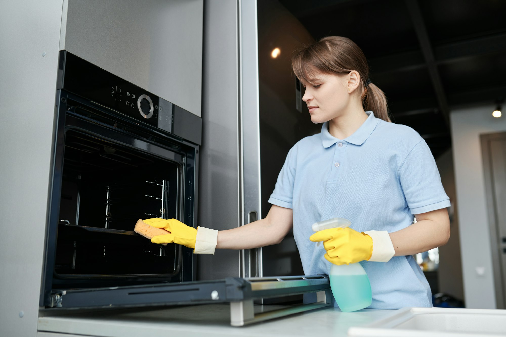 Woman cleaning the oven in the kitchen