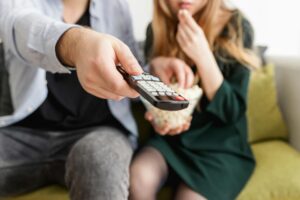 Couple using a remote control while eating popcorn